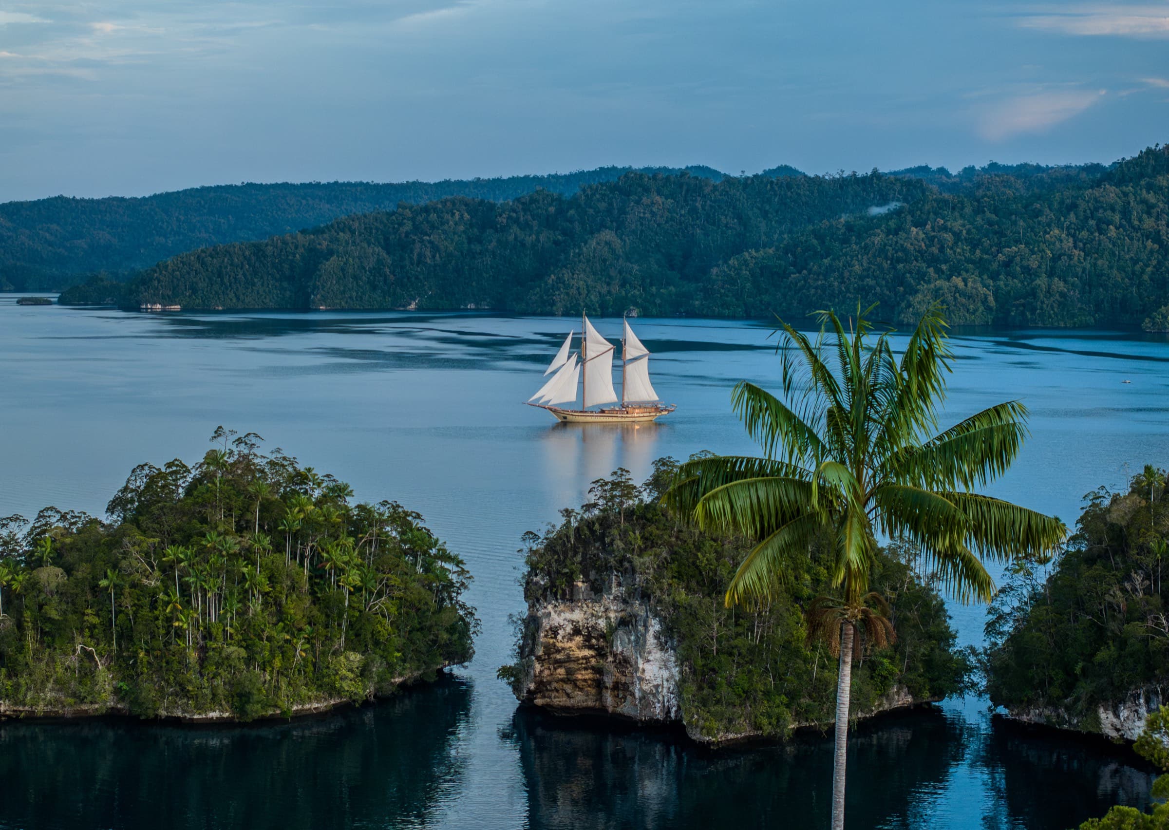 A sailing yacht at anchor among the karst islands of Raja Ampat at first light